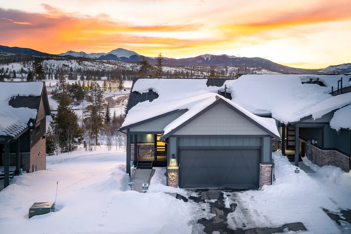A scenic exterior shot of the chalet’s snow-covered roof and garage, set against a dramatic mountain sunset. The cozy atmosphere combines the invitation of a mountain retreat with hints of adventure, as the landscape suggests opportunities for skiing and exploring, while the warm sunset light emphasizes comfort and serenity.