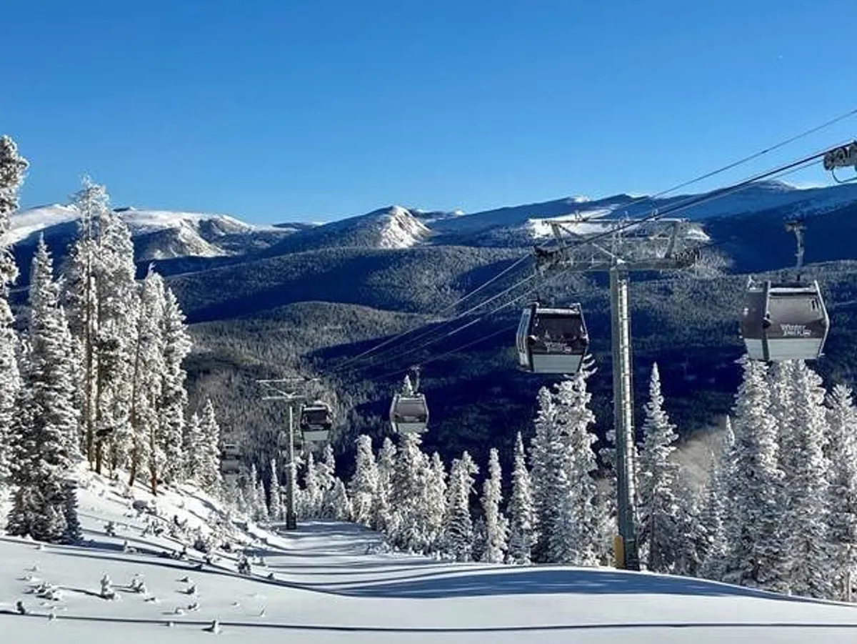 This image features ski gondolas gliding above snow-covered trees against a majestic mountain range, perfectly capturing the spirit of winter adventure and the immediate access to world-class skiing and snowboarding at Winter Park Resort.
